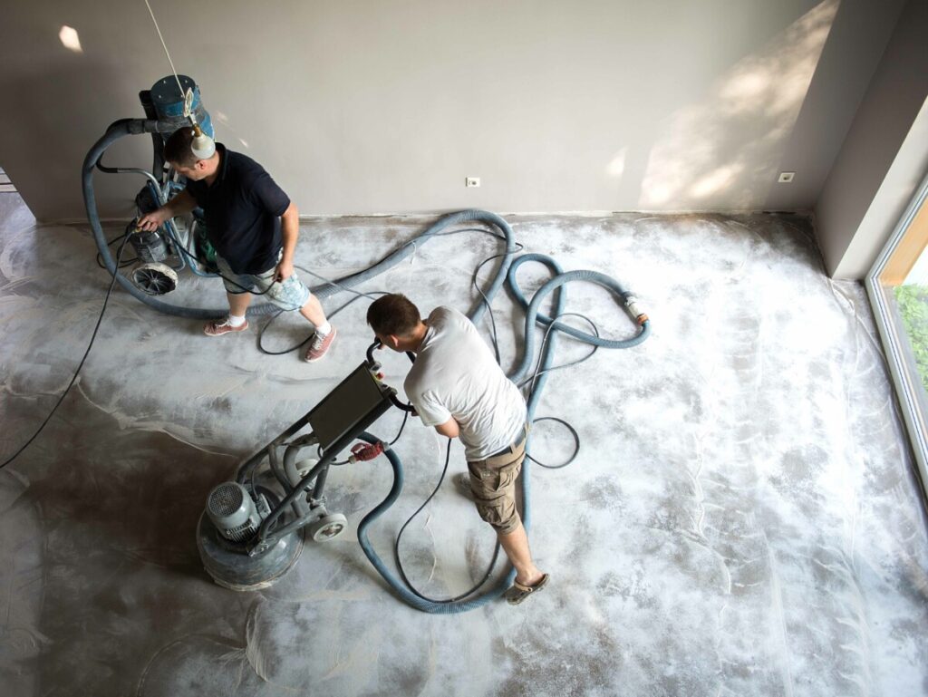 Construction worker in a family home living room that grind the concrete surface before applying epoxy flooring.Polyurethane and epoxy flooring.Concrete grinding.